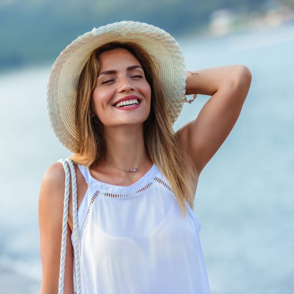 Happy young beautiful woman walking alone on the beach